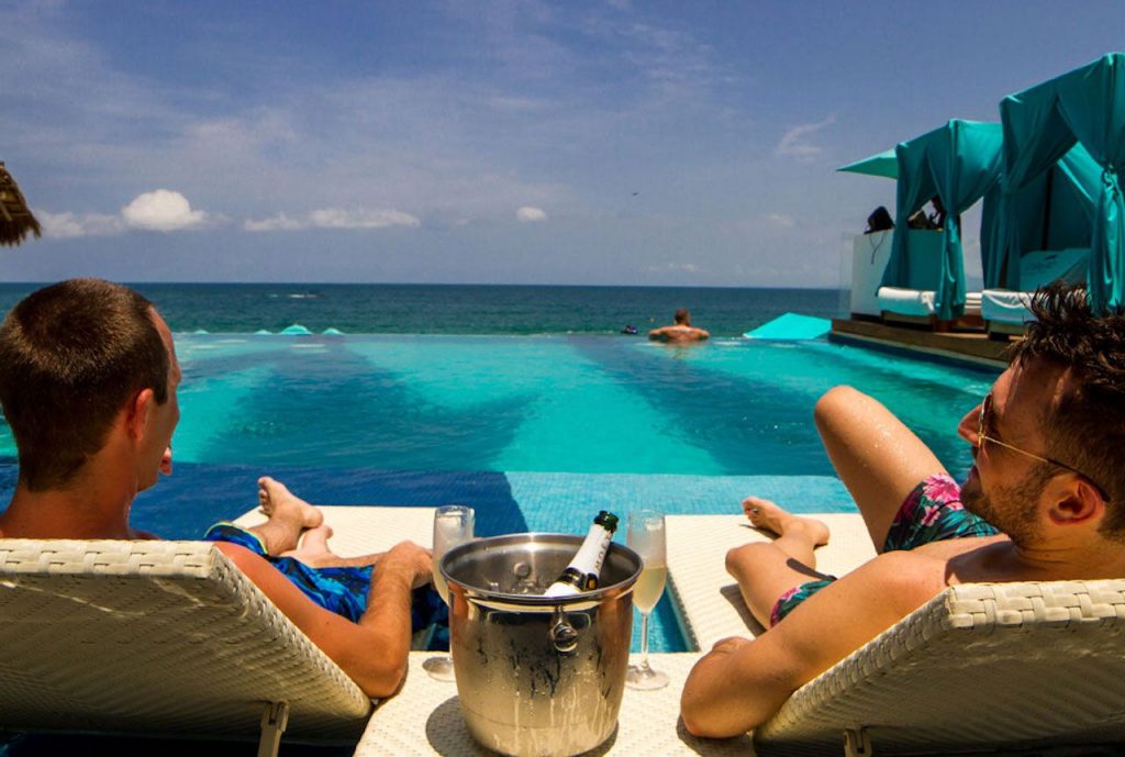Gay couple lounging be the pool in Mexico
